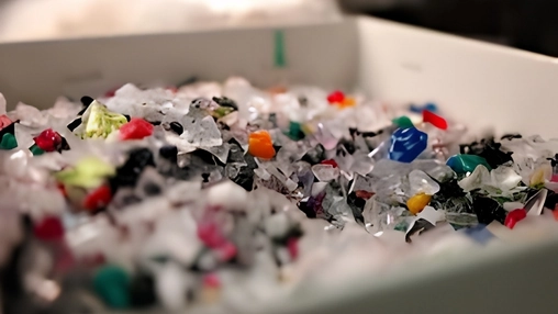 Close-up of mixed shredded plastic fragments in white and multicoloured pieces collected in a white tray