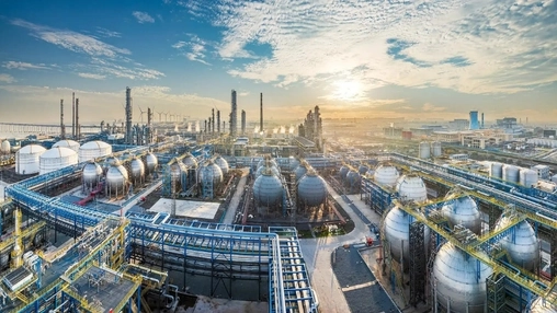 Aerial view of an integrated petrochemical complex with spherical tanks, towers, and blue piping at sunrise
