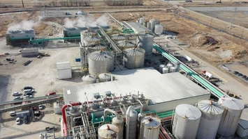 Drone shot of a biofuel plant with grain silos, conveyor systems and steam venting from processing units