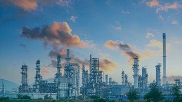 Petrochemical plant at twilight with distillation columns and pipe networks against a blue and orange sky